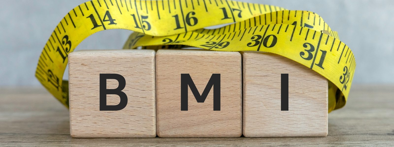 BMI Concept with Wooden Blocks and Measuring Tape on Wooden Surface