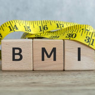 BMI Concept with Wooden Blocks and Measuring Tape on Wooden Surface