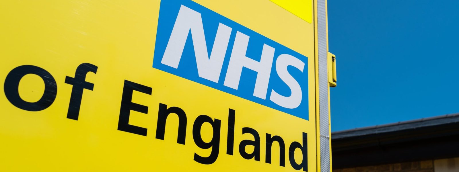 Close-up of a parked NHS ambulance showing the NHS logo and text