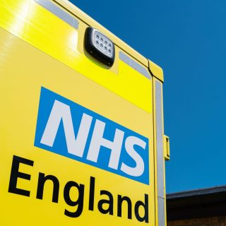 Close-up of a parked NHS ambulance showing the NHS logo and text