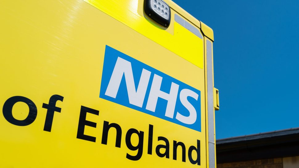 Close-up of a parked NHS ambulance showing the NHS logo and text